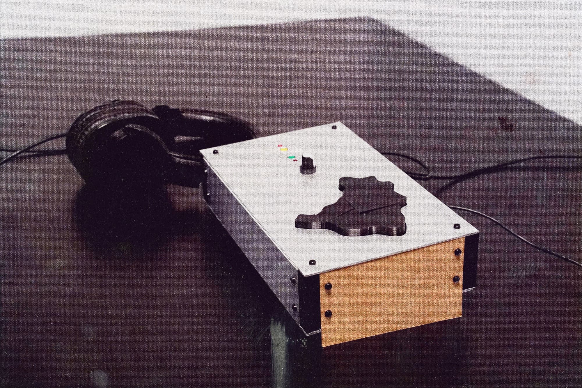 The installation on a dark table: an aluminum enclosure with the Brazil map cut into puzzle-piece buttons, a knob, status LEDs, and headphones plugged in