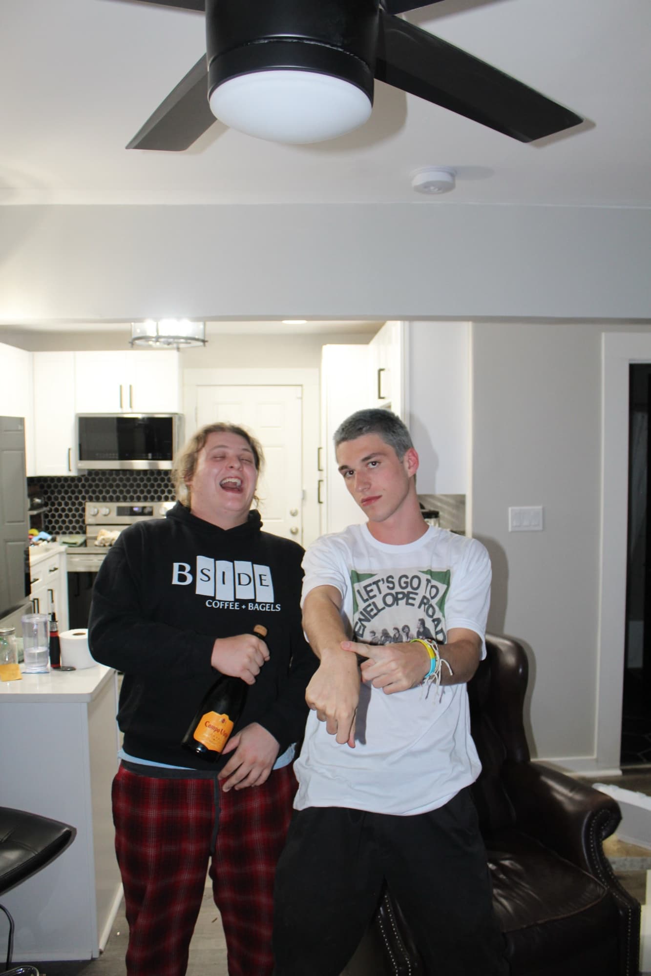Two band members at home wearing EP merch: a black hoodie and a white tee printed with the cover artwork